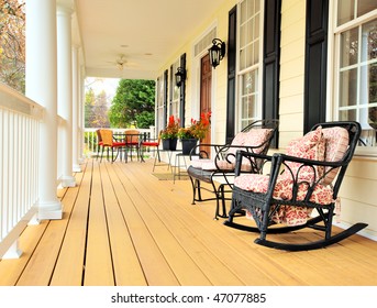 Low angle view of a large front porch with furniture and potted plants. Vertical format. - Shutterstock ID 47077885