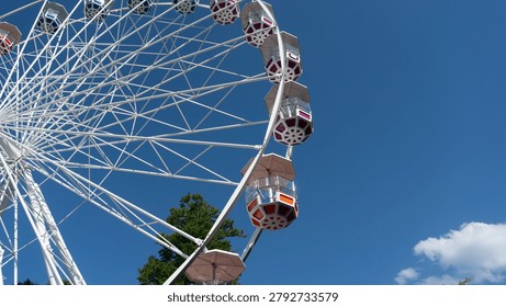Low angle view of a large white ferris wheel against a clear blue sky