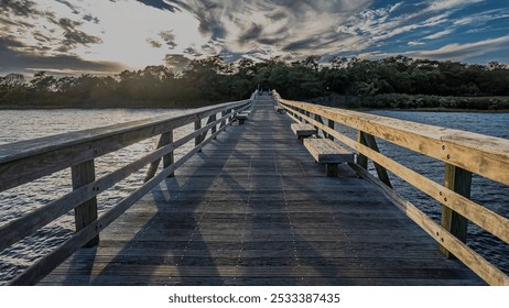 A low angle view of a long wooden pier on a sunny day with clouds in the blue sky. - Powered by Shutterstock