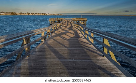 A low angle view of a long wooden pier on a sunny day with clouds in the blue sky. - Powered by Shutterstock