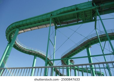 Low angle view looking up at an empty green roller coaster.