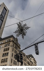 A low angle view looking up at the giant star hanging over the intersection of 57th Street and Fifth Avenue in NYC on a cloudy day.