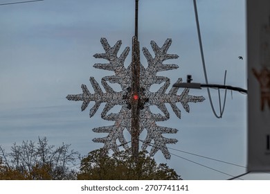 A low angle view looking up at the giant snowflake hanging over the intersection of 57th Street and Fifth Avenue in NYC on a cloudy day.