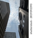 Low angle view looking up at high-rise modern skyscrapers against a bright blue sky with light clouds.