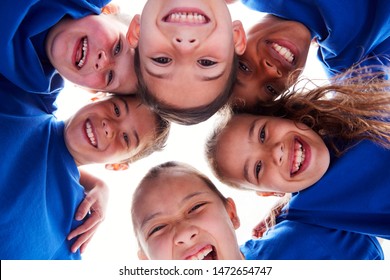 Low Angle View Looking Up Into Faces Of Children In Huddle On Sports Day