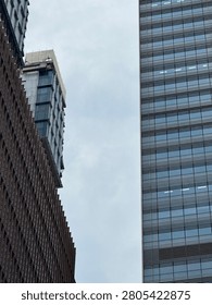 Low angle view looking straight up at a narrow sliver of cloudy sky positioned perfectly between two gigantic modern office skyscrapers.
