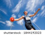 Low angle view of a male athlete with discus throw disk with blue cloudy sky in the background