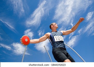 Low angle view of a male athlete with discus throw disk with blue cloudy sky in the background - Powered by Shutterstock