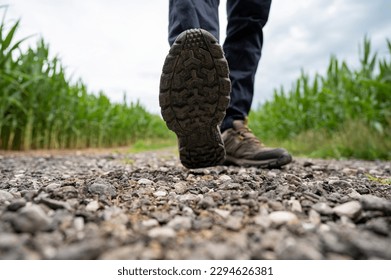 Low angle view of male feet in hiking boots stepping towards camera on a gravel country road. - Powered by Shutterstock