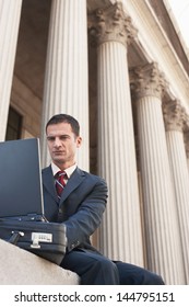 Low Angle View Of A Male Lawyer Using Laptop Outside Courthouse