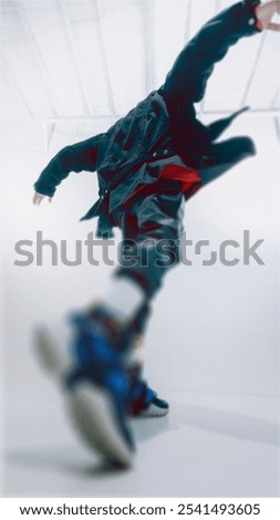 Low angle view of man in mid-motion, shows energetic movement with glass morphism blur effect. Focus on his raised arms and flowing jacket. Concept of modern lifestyle, fashion forward people.