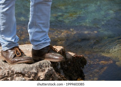 Low angle view of man standing on the rocky cliff, travel concept
