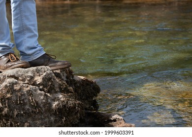 Low angle view of man standing on the rocky cliff, travel concept
