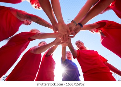 Low Angle View Of Manager Joining Hands With Womens Soccer Team During Pep Talk Before Match