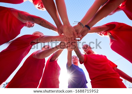 Low Angle View Of Manager Joining Hands With Womens Soccer Team During Pep Talk Before Match