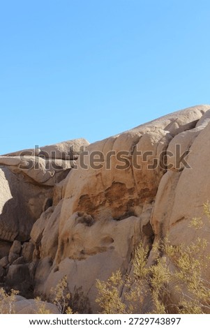 Low angle view of massive granite boulders and rock formations under a clear blue sky, Joshua Tree National Park, California