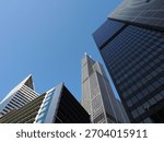 Low angle view of the massive Willis Tower framed by angular, dark glass and white contemporary buildings.