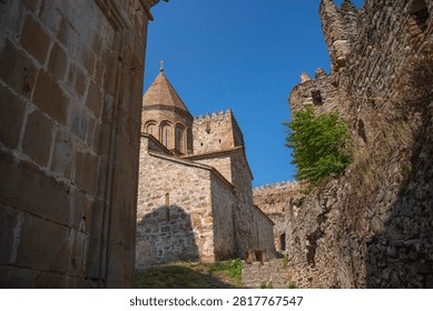 Low angle view of the medieval Ananuri castle complex showcasing ancient stone church architecture and defensive walls against a clear blue sky in Georgia