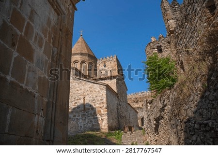 Low angle view of the medieval Ananuri castle complex showcasing ancient stone church architecture and defensive walls against a clear blue sky in Georgia