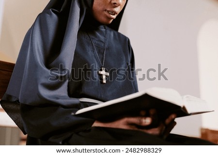 Low angle view medium closeup shot of African American sister reading prayer book, copy space