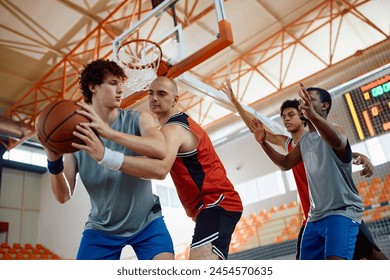 Low angle view of men playing basketball at an indoor court.  - Powered by Shutterstock