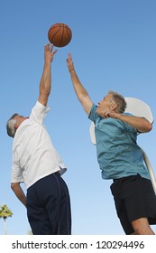 Low angle view of men reaching for the basketball at court