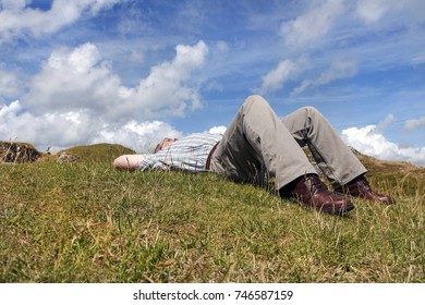 Low Angle View Of A Middle Aged Man Snoozing In A Public Park.