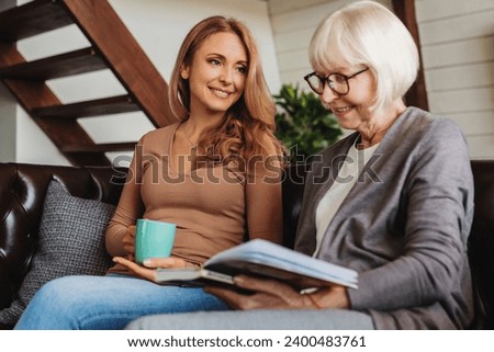 Low angle view of middle aged woman spending time with her senior mother at home. Relations between generations. Grandchildren visiting granny. Mother`s Day