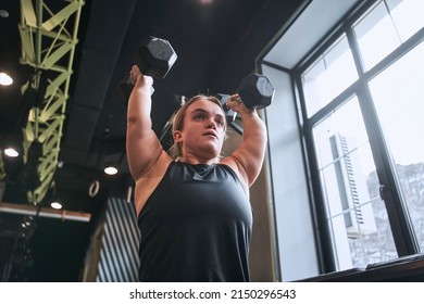 Low angle view of the midget woman lifting the dumbbells