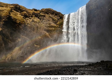 Low angle view of the mighty Skógafoss waterfall under a clear blue sky, with a beautiful double rainbow caused by its constant spray, near Route 1, Ring Road, Southern Region, Iceland