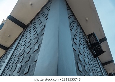 Low Angle View Of A Modern Building Corner With Textured Geometric Patterns Under A Clear Blue Sky