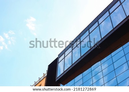 Low angle view of modern building with tinted windows against blue sky