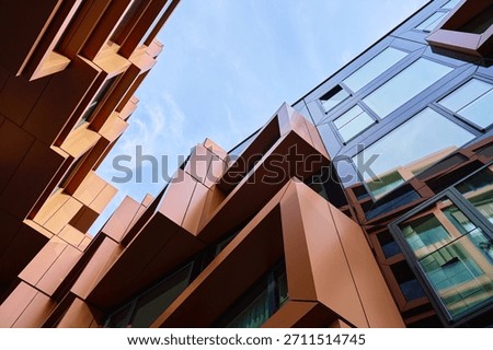 Low angle view of a modern building with angular metal panels and large glass windows. Concept of contemporary architecture, geometric design and urban construction.