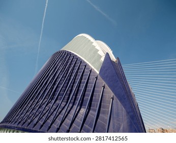 Low angle view of a modern cable stayed bridge tower with sweeping cables against a clear blue sky, creating a striking architectural skyline scene.
