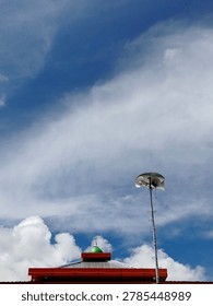 Low angle view of a modern mosque loudspeaker and a mosque roof structure against a vast cloudy blue sky