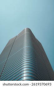 Low angle view of a modern skyscraper against a clear blue sky, showcasing architectural design and urban development.