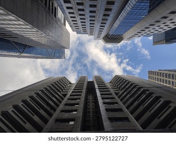 Low angle view of modern skyscraper architecture against a blue cloudy sky.