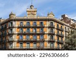 A low angle view of a modernist building in Barcelona, Spain, with its grand facade windows against the sky of an estate neighborhood.