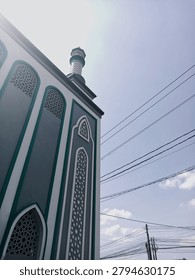 Low angle view of mosque architecture with minaret and sunlight, showcasing Islamic design and spiritual heritage.