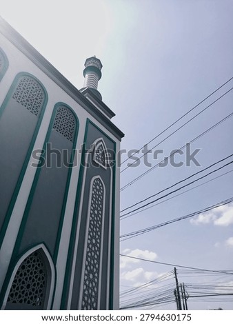 Low angle view of mosque architecture with minaret and sunlight, showcasing Islamic design and spiritual heritage.