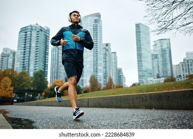 Low angle view of motivated athletic man running during rainy day. Copy space. - Powered by Shutterstock