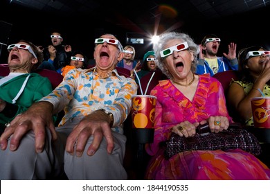 Low Angle View Of A Movie Audience In 3D Glasses With Popcorn And Drinks And Scramming While Watching A Horror Movie.