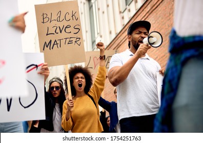 Vista desde un ángulo bajo del multiétnico grupo de personas que apoyan el movimiento Black Lives Matter y protestan en las calles de la ciudad. 