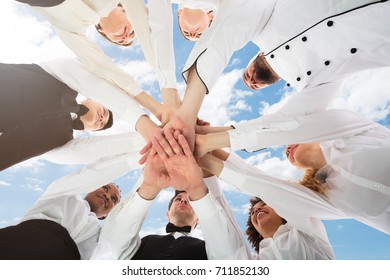 Low Angle View Of Multiracial Restaurant Staff In Uniform Stacking Hands