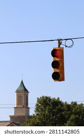 Low angle view of municipal traffic light signals suspended on overhead utility wires over a small town intersection crossroad.