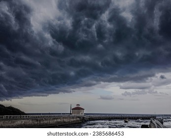 a low angle view of nature as an impending storm casts an ominous beauty over a Florida pier, where the clash of serene waters and gathering dark clouds and rough waters.