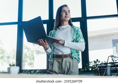 Low Angle View Of Nonbinary Person Holding Laptop In Creative Agency