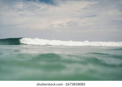 Low angle view of ocean wave approaching under cloudy sky.