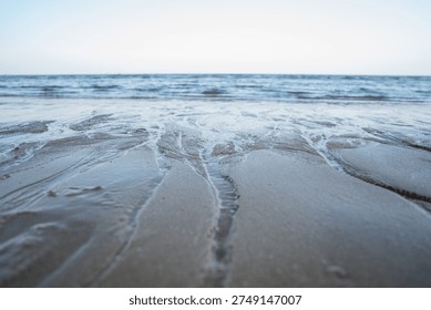 Low angle view of ocean waves approaching the sandy beach with natural water patterns.