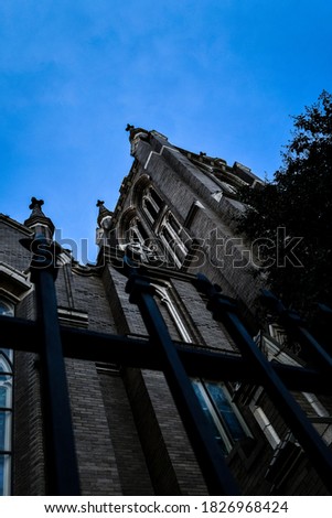 Low angle view of a old cathedral church in downtown Houston, Texas. Wrought iron fence in view with a blue sky background.